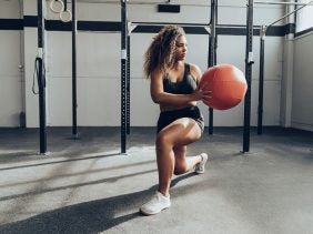 Eine Frau macht Ausfallschritte mit einem Medizinball